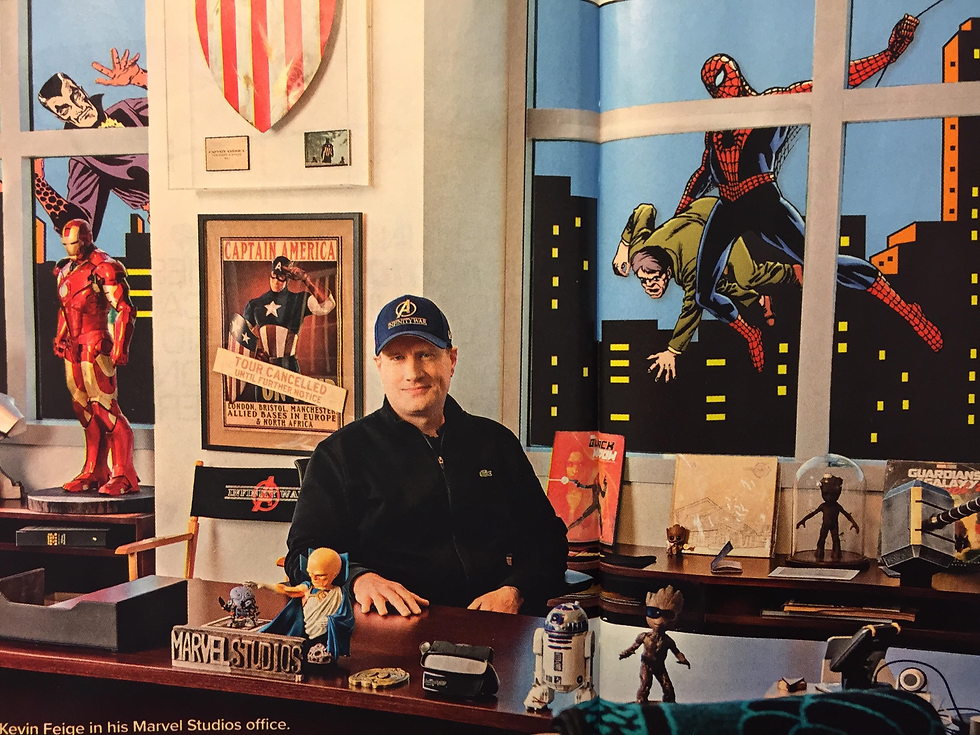 a man sitting at a desk surrounded by comic book paraphernalia