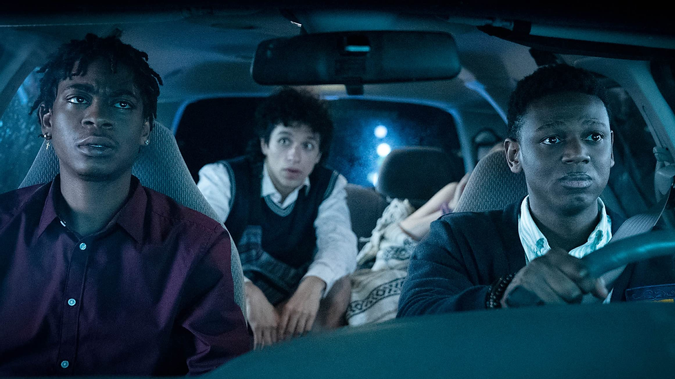 two African American men are sitting in the front seats of a van, one is driving, while another man is sitting in the backseat with a passed out girl