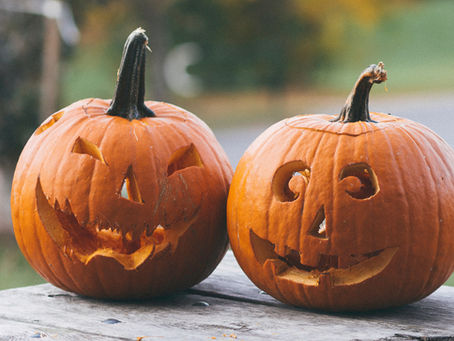 two carved pumpkins on a table outdoors