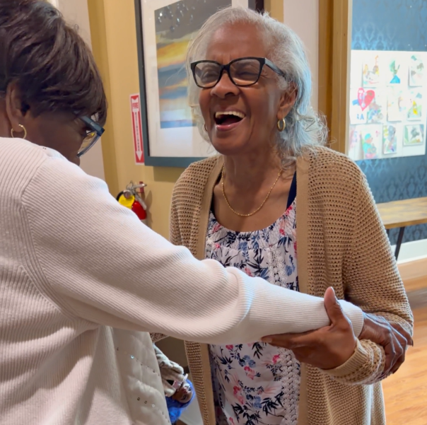Two older adults joyfully greeting each other indoors