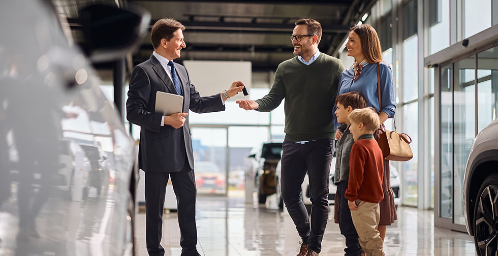 Happy salesman giving new car key to a family in auto salon .jpg