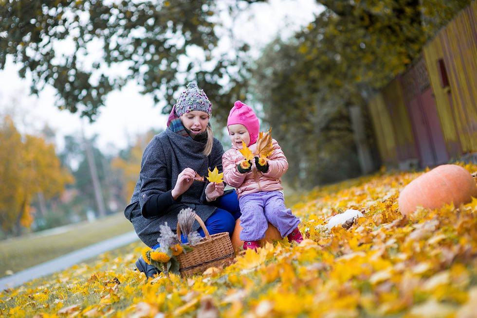 mon and small child picking leaves in park