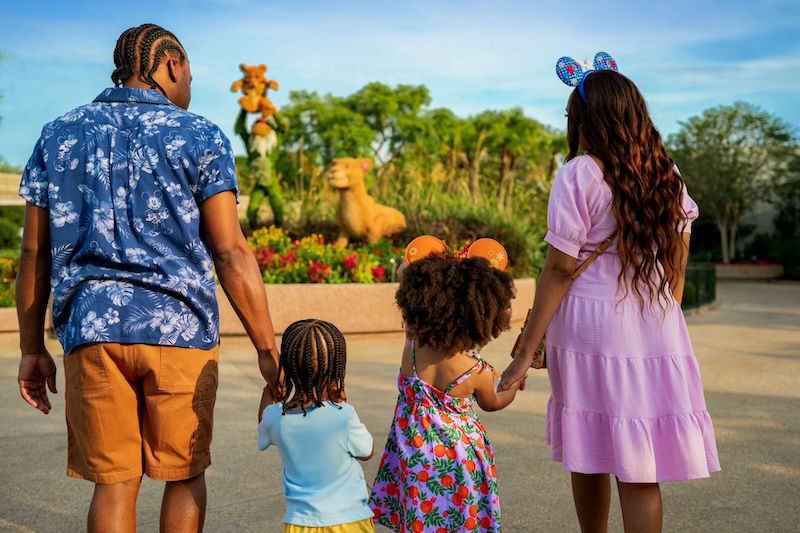 A family walking past a Disney Lion King character topiary during the spring festival at EPCOT.