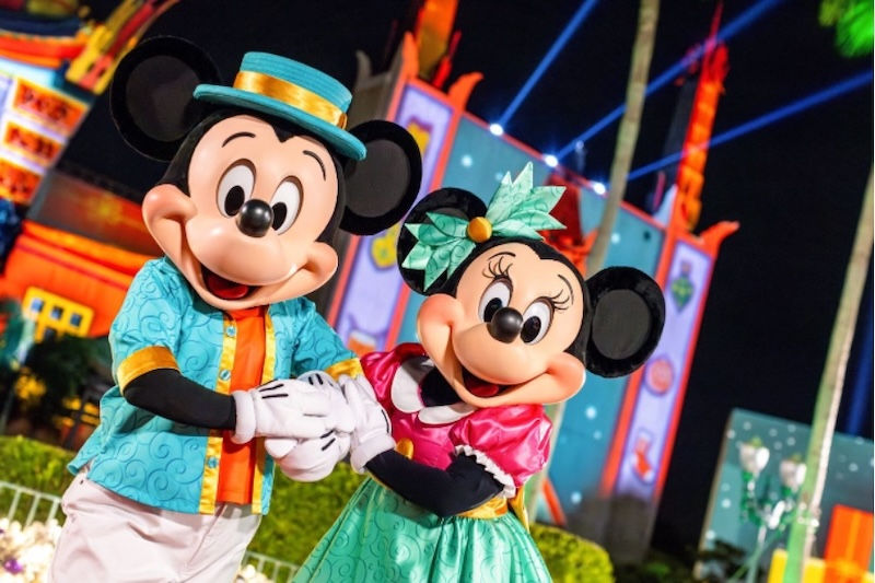 Mickey Mouse and Minnie Mouse in custom tropical teal and pink holiday outfits smiling together at Disney's Hollywood Studios.