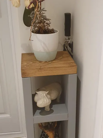 Narrow grey and wood shelf with plant and white figurine