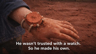 a wrist watch made of red clay on a boys hand