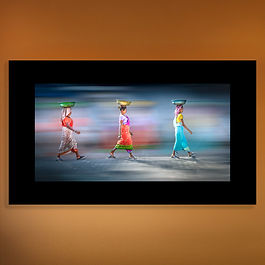 <p class="font_8">Le long des voies ferrées de Mumbai, trois femmes avancent d’un même pas, portant sur leur tête le poids du quotidien avec une grâce presque chorégraphiée. Leurs saris éclatants illuminent la scène, rappelant que la beauté et la dignité peuvent fleurir même au cœur de l’effort. Dans ce ballet silencieux, la résilience devient élégance.</p>