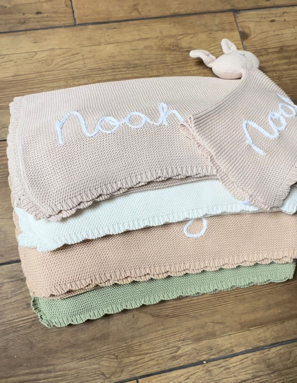 Organic cotton blankets in a pile including bunny comforter and showing "Noah" name embroidery