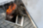 Flames and smoke coming out of the window of a burning wooden house.jpg