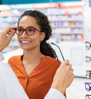 African young woman in optic store choosing new cool-down glasses with optician. Mixed rac