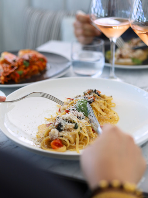 A plate of pasta with sea food and a person holding their cutlery ready to eat the dish