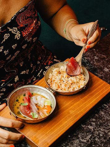 A woman eating an advanced dish of raw fish and other seafood