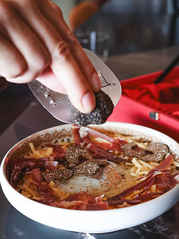 A closeup of tapas dish being finalized by the chef in slicing truffle