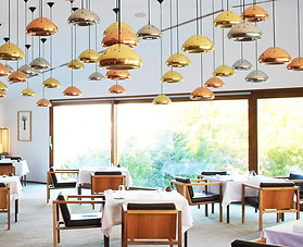 a restaurant with wooden chairs, lights with golden pendants