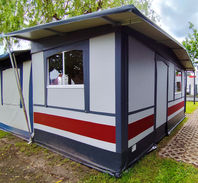 Perspektive von der Seite, die den gepflasterten Gehweg neben dem Zelt und die geöffnete Schiebetür im Eingangsbereich zeigt. Vorzelt für Dauercamper mit 5 Meter Breite, 2,50 Meter Tiefe und umlaufendem Dachüberstand.