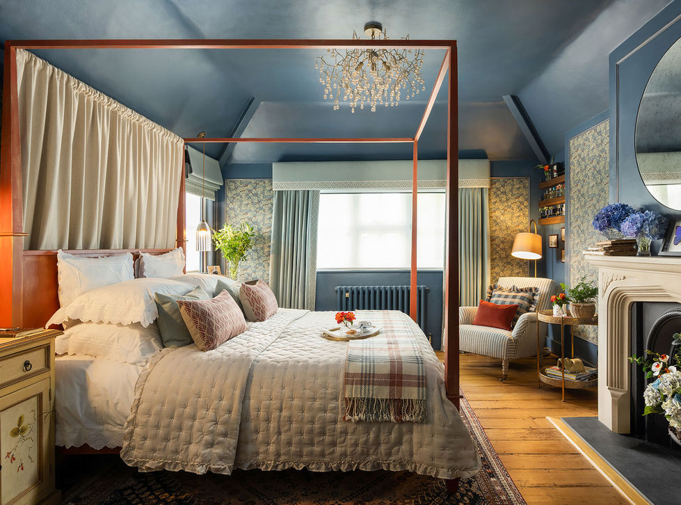 Luxury primary bedroom with four-poster bed, blue walls and bespoke soft furnishings