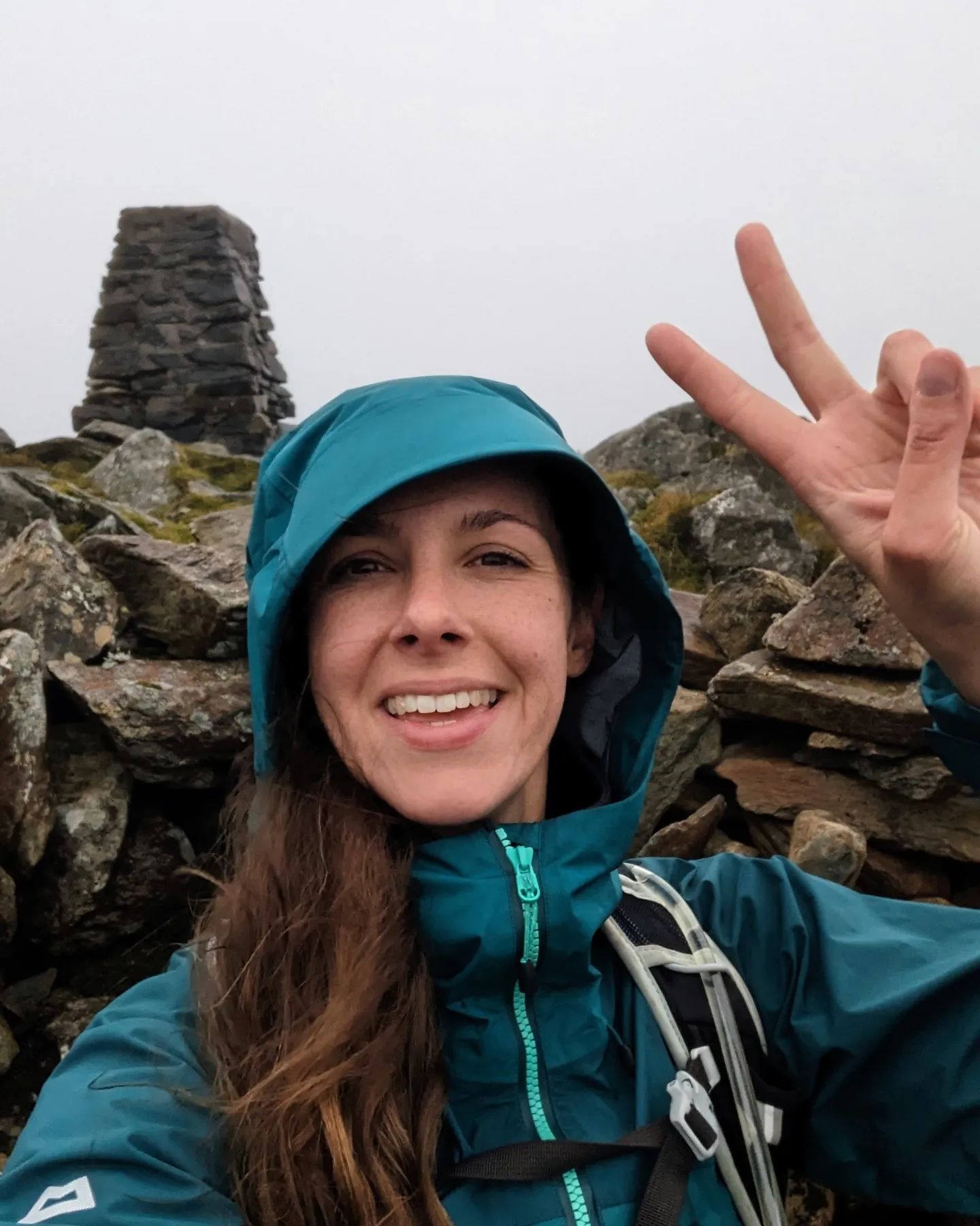 Girl at the Rhinog Fawr trig point giving the peace sign