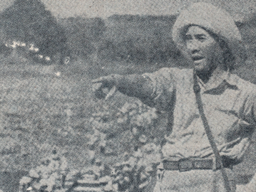 Sukarno mengenakan celana pendek dan topi jerami serta memegang sekop dan menunjuk ke kejauhan. Foto ini diambil ketika Sukarno menjadi salah satu tokoh terkenal yang terlibat dalam kegiatan romusha sukarela di Bogor pada 1944. (Wikimedia Commons).