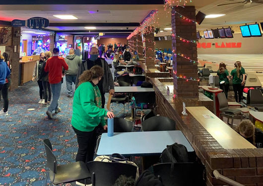 Guests enjoying food and bowling under colorful string lights at King’s Entertainment.