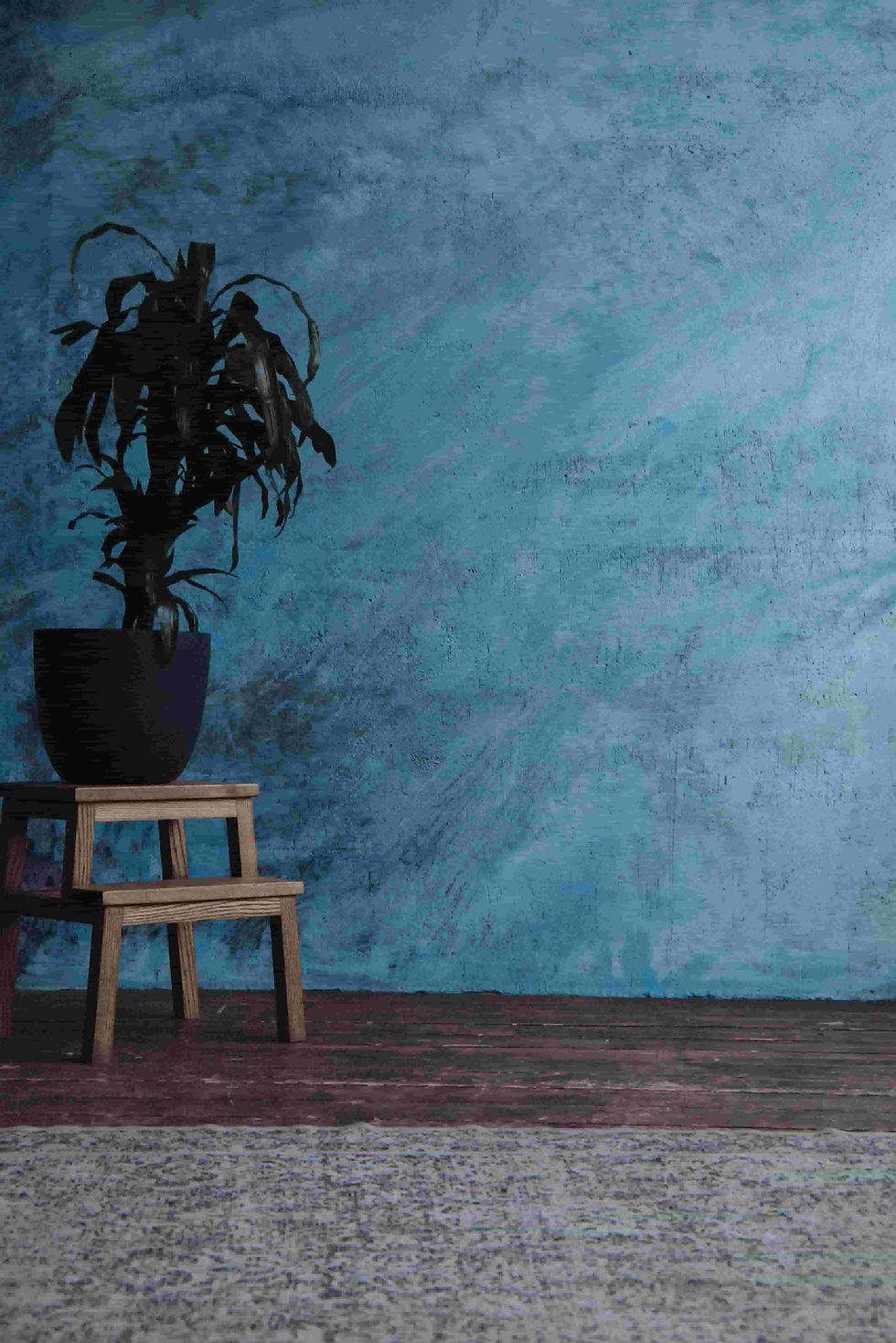 Pared pintada de azul con una planta y una alfombra, mostrando el aspecto final después de imprimar y pintar, preguntando si era necesario lijar.