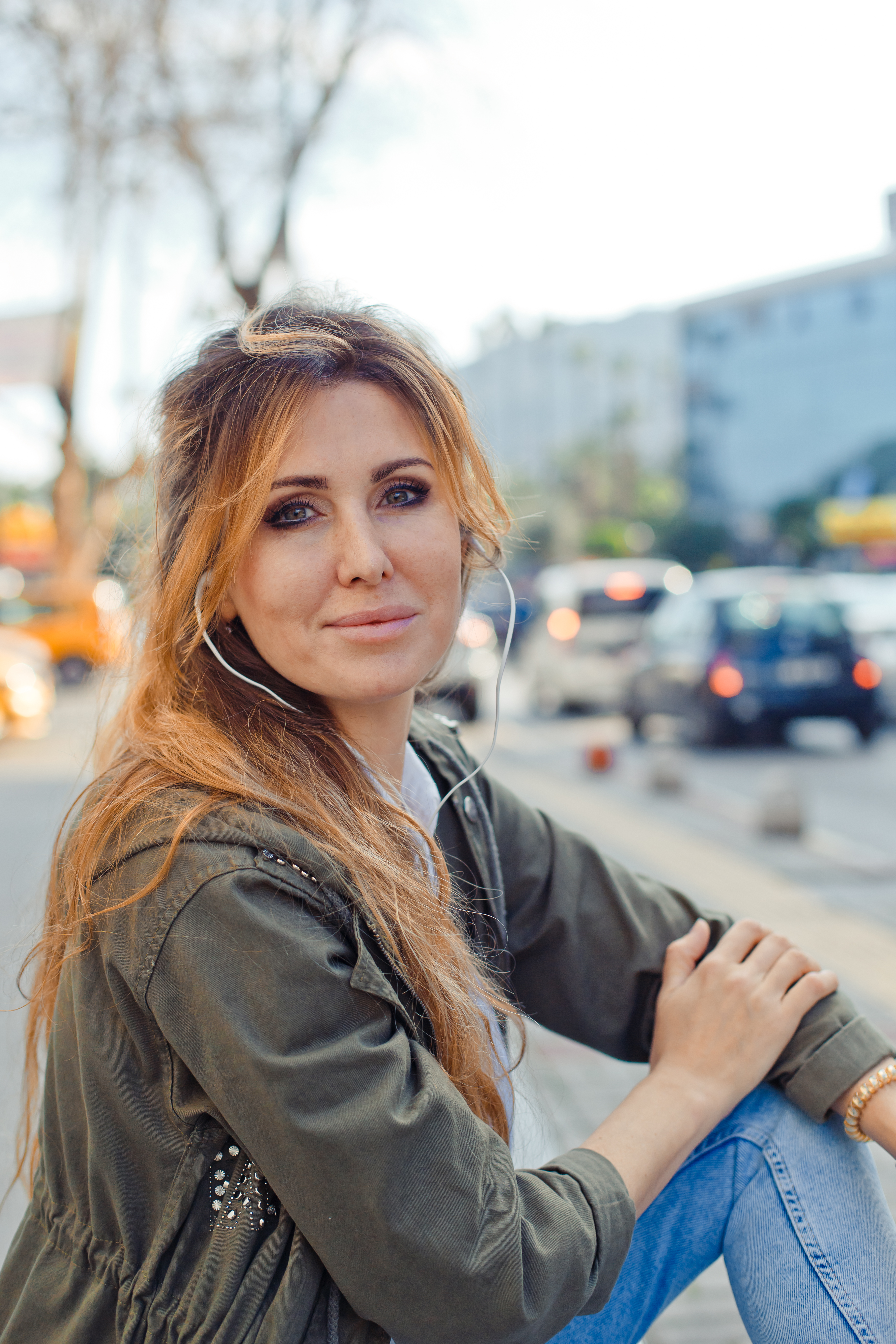beautiful-woman-sitting-bench-slightly-smiling-listening-music-street-daytime.jpg