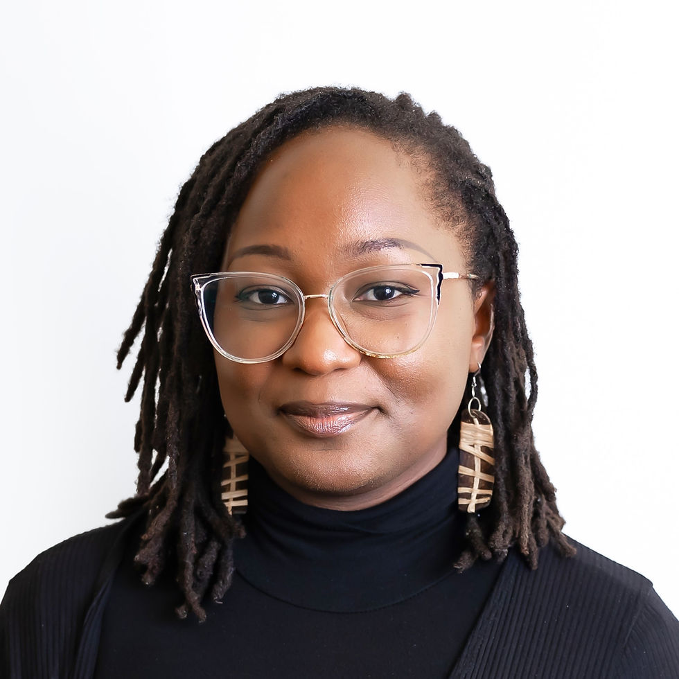 Headshot of Yemilo smiling against a white background. Her hair is styled in locs. She is wearing clear-framed glasses, geometric wooden earrings, and a black turtleneck.