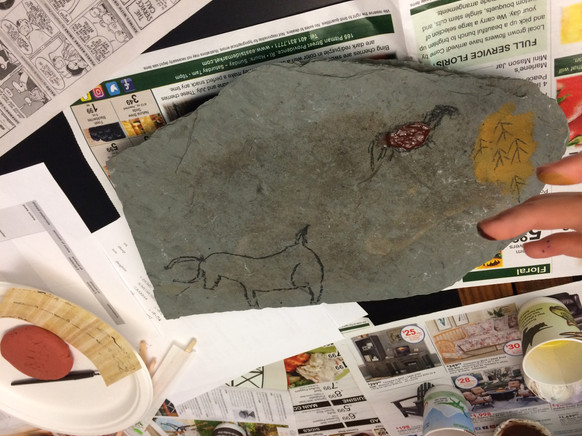 Students making "cave paintings" using a stone slab and ochre
