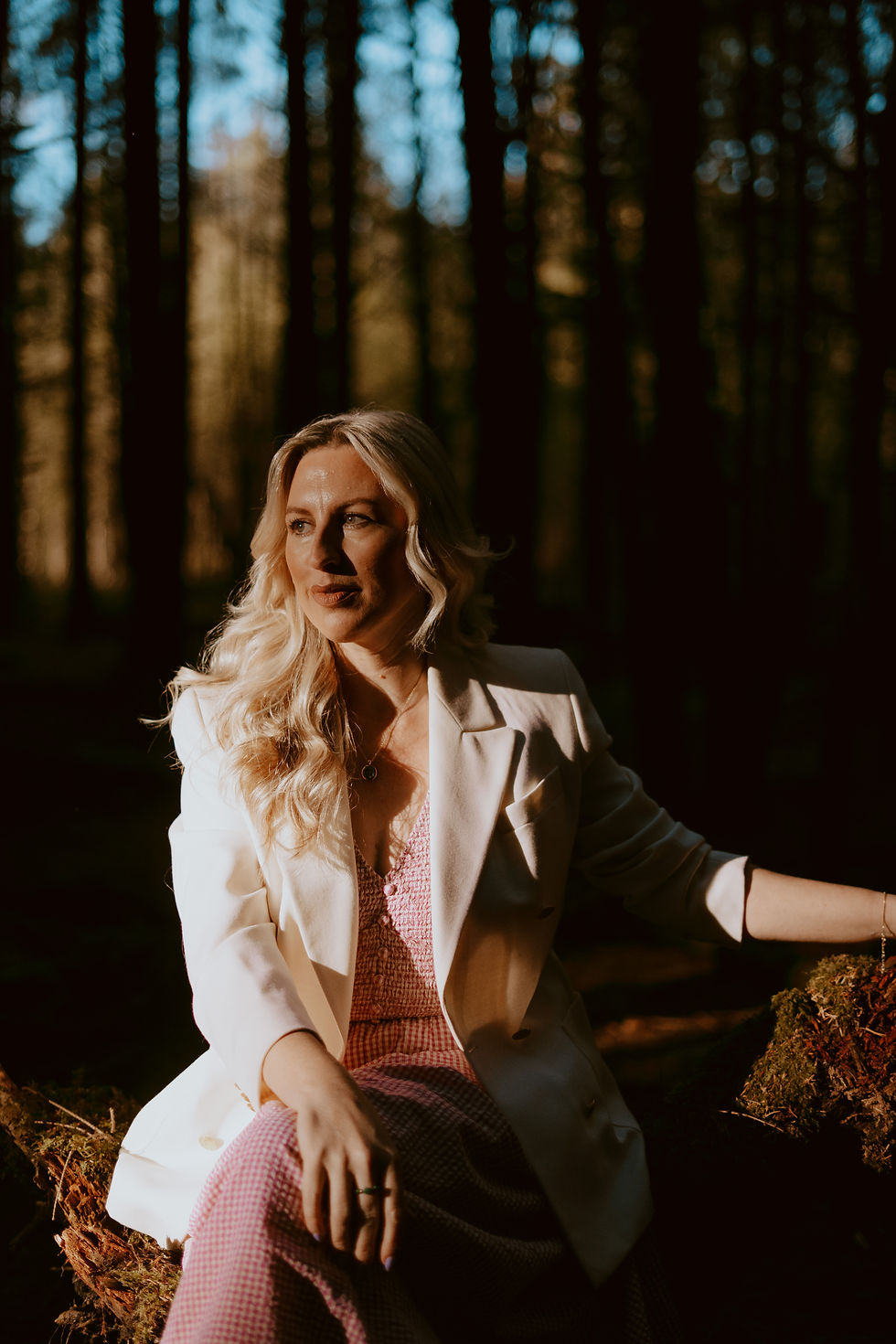 A well-dressed woman sitting in a woodland setting