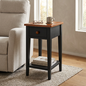 The Ipswich handcrafted early American chairside table in Historic Charcoal soft maple with a Heritage Amber cherry top beside an upholstered chair.