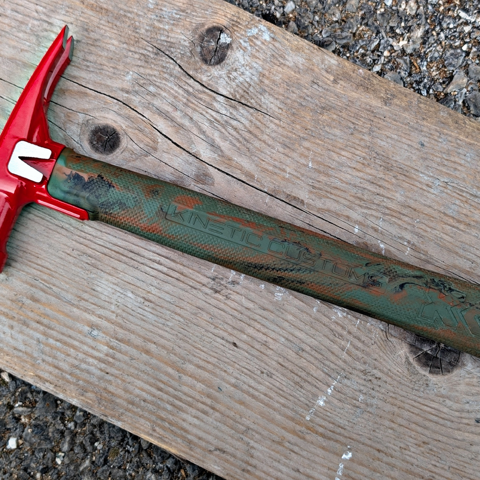 E12 woodland camo electricians hammer with red head on wood.