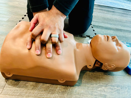 Adult CPR - Person's hands performing chest compression on CPR manikin.