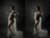 Woman in sheer white maternity gown against dark backdrop in Oregon studio