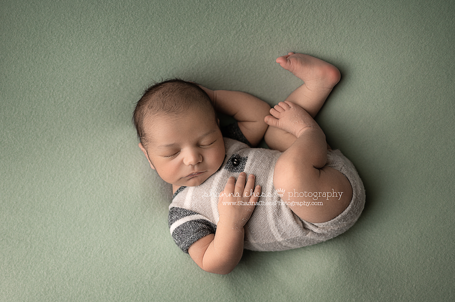 Newborn boy curled up on back asleep