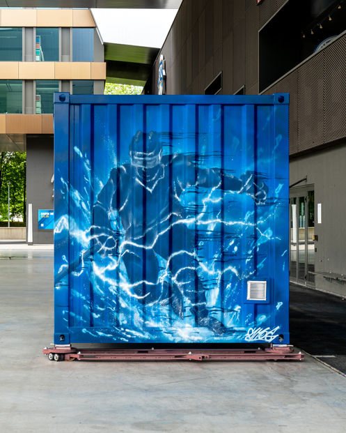 Die fertige Seitenwandbemalung eines umgebauten Containers, der als neuer Food-Stand des Eishockeyklubs EV Zug dient. Die Bemalung zeigt einen dynamischen Hockeyspieler auf blauem Hintergrund mit blitzartigen Effekten.