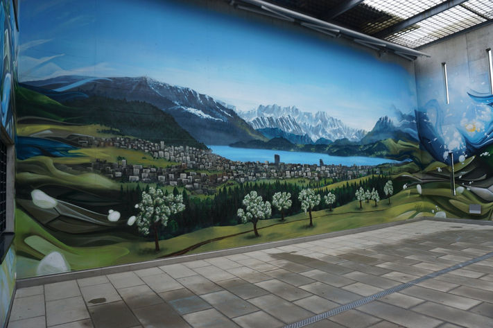 Wandmalerei im Spazierhof der Strafanstalt Bostadel mit Bergsee, Blumenwiese und ruhiger alpiner Landschaft.