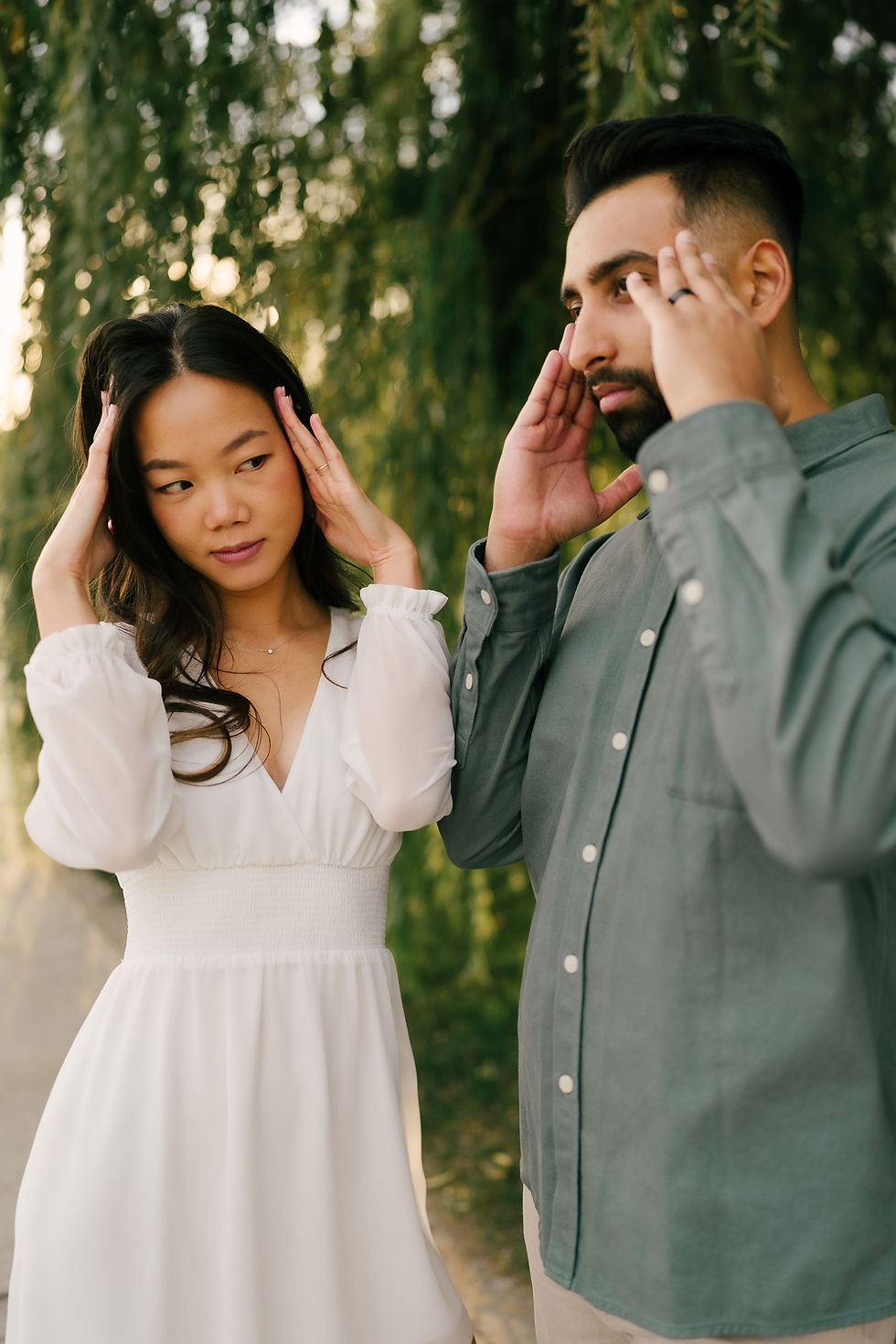 An intimate photo of a stylish couple standing outdoors, holding hands and smiling, taken during a natural light couples photography session in Alberta by an artistic Calgary couples photographer.