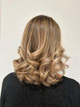 Dos de femme, cheveux ondulés blonds méchés, coupe élégante.