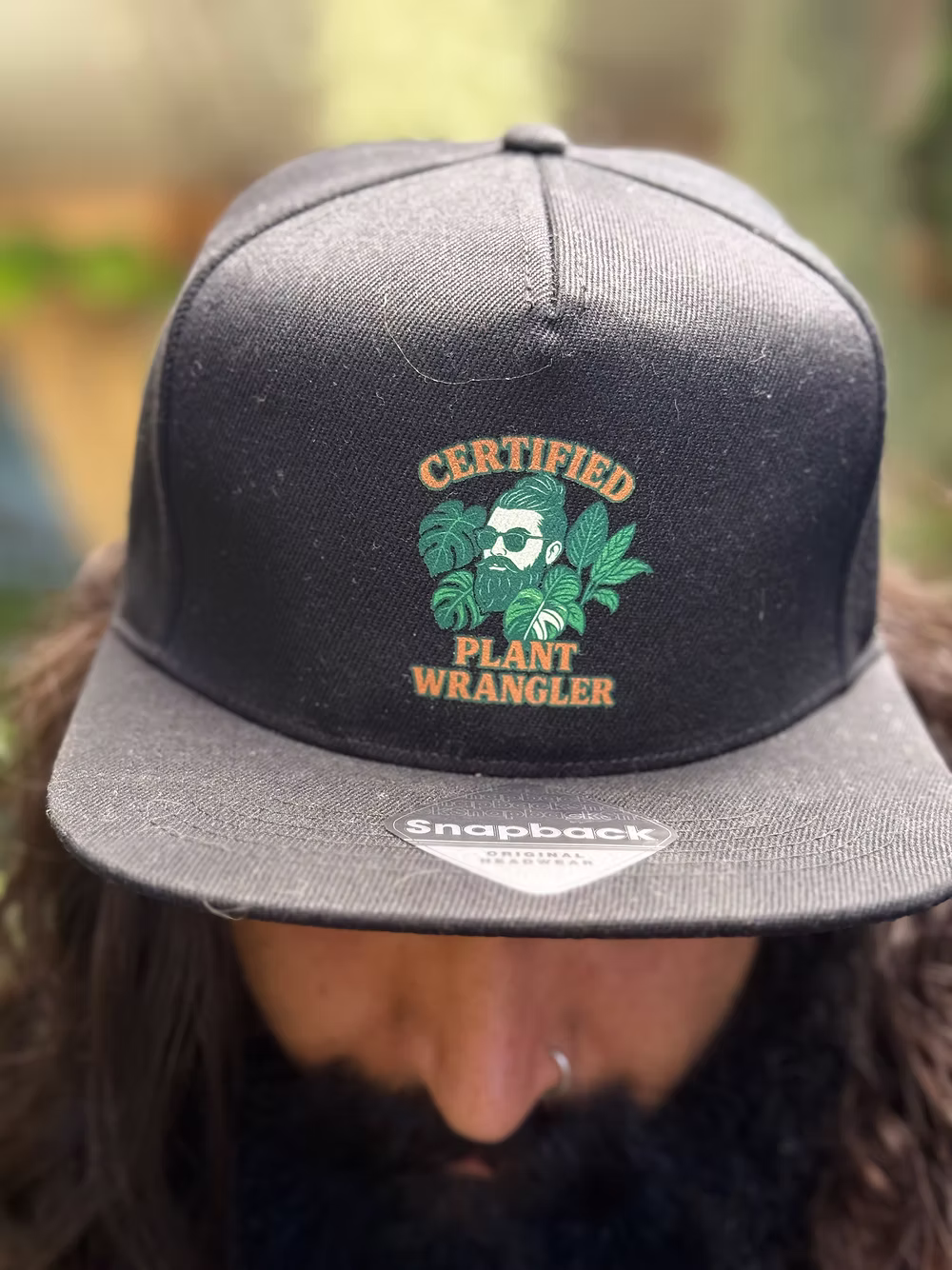Close-up of the exclusive TheBeardedPlantaholic snapback cap showing the logo.