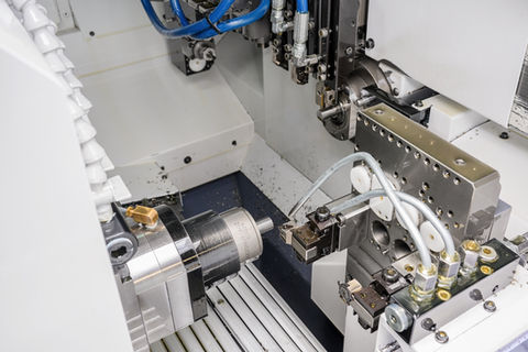 Detailní záběr obráběcího stroje, kovové části, CNC dlouhotočné obrábění a technologický proces.