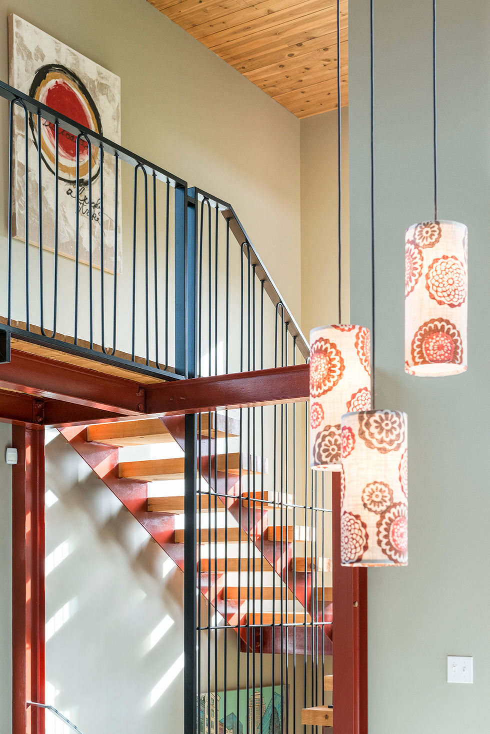 Modern pendant lights illuminate a staircase with a decorative art piece and design.