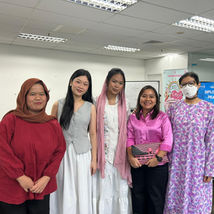 Five women smiling, standing together in an office
