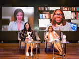Panel discussion with two women on stage and two on screen.