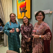 Three women in patterned dresses smiling