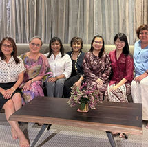 Six women smiling, seated on a sofa