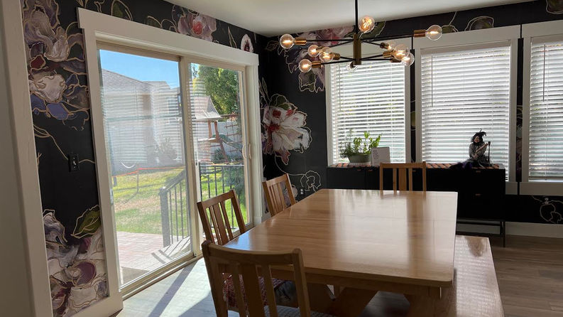 After picture of a dining room with large floral wallpaper and back door