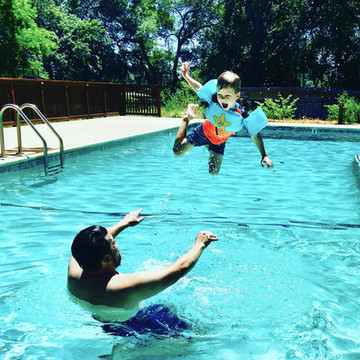 Father and child with floaties playing in pool