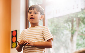 Confident little boy trained at Stand Up and Speak, stands in front of classroom delivering a speech