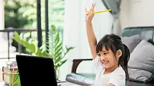 A young girl taking notes in an Online Public Speaking Class for Primary Students