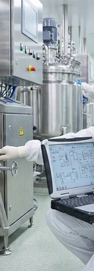 A clean and controlled pharmaceutical production room where an engineer in full cleanroom PPE is inspecting a stainless steel processing vessel. They’re using a rugged laptop displaying a technical schematic while making an adjustment to the equipment. The scene highlights technical operations, equipment troubleshooting and process engineering inside GMP environments.