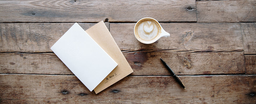 Solid wood counselling desk with a latte, pen, and journal on top for writing notes